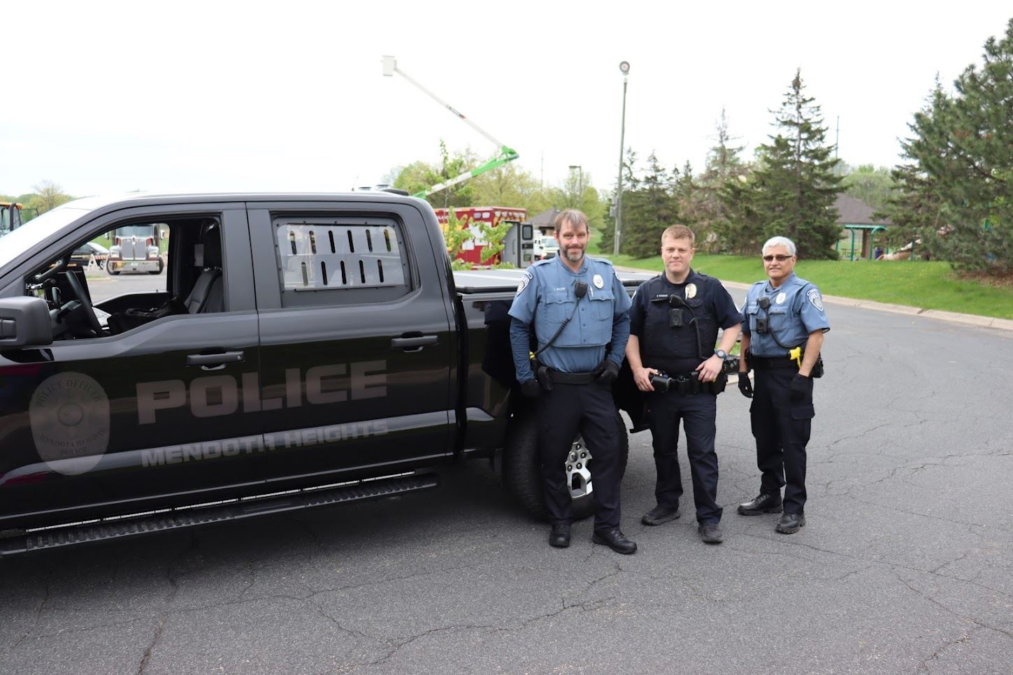 Three police officers pose by squad truck