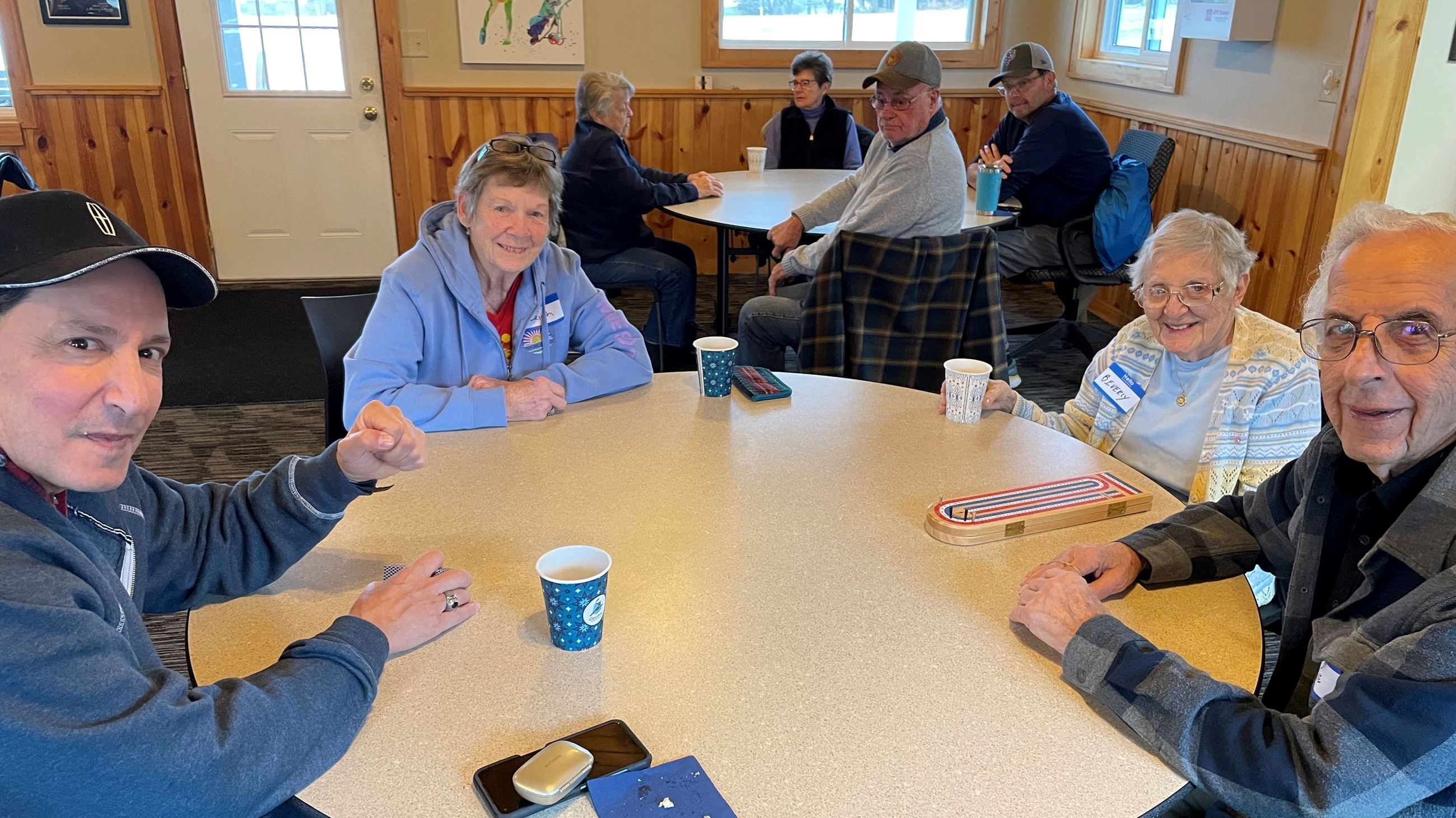Group of 4 adults smiles for camera as they play cribbage